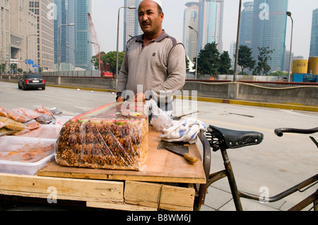 Ein Uyghur Muslim aus Xinjiangs verkauft traditionelle Süßigkeiten und Nüssen in den Straßen von Pudong, Shanghai. Stockfoto