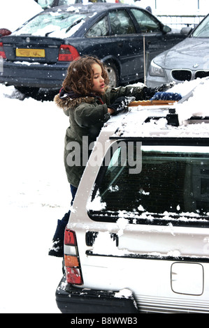 Gemischte Rennen junge Bürsten Schnee von seiner Familie Auto nach / während heftige Schneefälle in London. 2. Februar 2009. Stockfoto