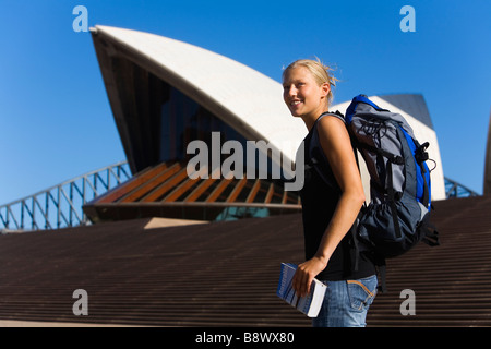 Junge Backpacker mit Anleitung Buch stand vor dem Sydney Opera House, Sydney, New South Wales, Australien. Stockfoto