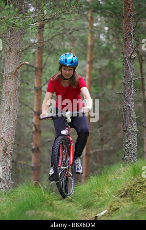 Frau (im Alter von 30-35 Jahre alt) fahren Mountainbike durch Kiefernwald Stockfoto