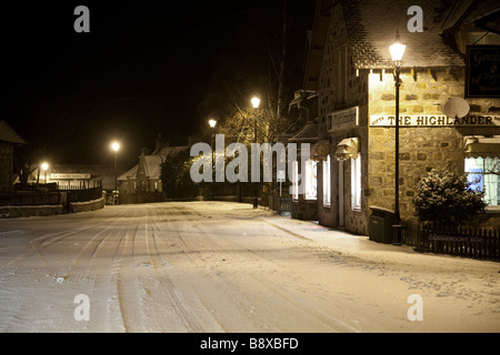 Die Häuser und Geschäfte auf einem Schnee Winter Nacht im abgelegenen Hochland Braemar Village, Aberdeenshire, Schottland, Großbritannien Stockfoto