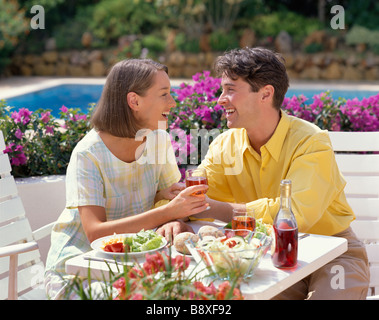 junges Paar Essen und trinken Wein auf der Terrasse am Swimmingpool Stockfoto