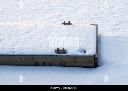 Einsame Pier im Hafen bedeckt mit Schnee am Sonnenuntergang Detail. Stockfoto