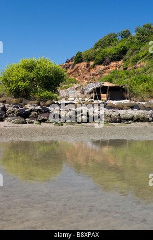 Hütte am Strand mit einsamen Baum spiegelt sich im Wasser. Stockfoto