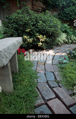 KALKSTEIN-BANK UND GESCHWUNGENEN PFAD DER RECYCLING-STONE STREET FERTIGER IN MINNESOTA GARTEN.  SOMMER. Stockfoto