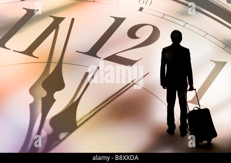 Silhouette eines Mannes hält einen Koffer im Hintergrund eine große Uhr Stockfoto