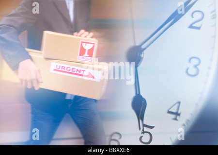 Mann, hält die Kontrollkästchen für die Dilivery im Hintergrund einer Uhr Stockfoto