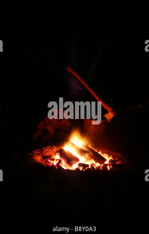 Ein Lagerfeuer mit Hackgut und Axt im Hintergrund Stockfoto