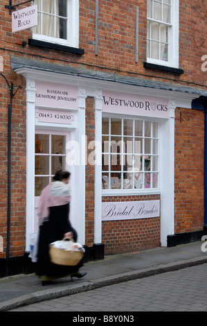 Frau mit Korb Einkaufskorb in Bewegungsunschärfe Weitergabe Juweliergeschäft Church Street, Godalming, Surrey, England Stockfoto