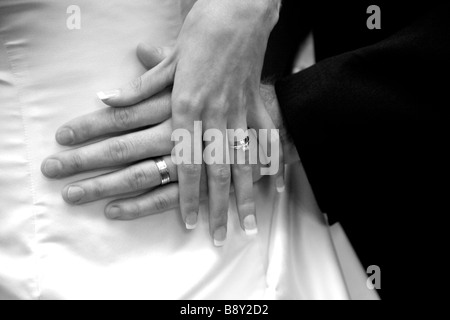 Nahaufnahme von Braut und Bräutigam, die ihre Eheringe gegen das Brautkleid zeigen. Stockfoto