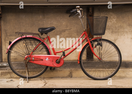 Eine rote Push Fahrrad parkt gegen ein traditionelles Gebäude in der japanischen Stadt Narai während einer Schnee-Bö Stockfoto