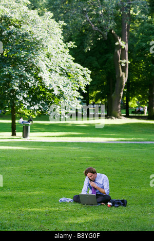 Ein Mann mit einem Laptop in einem Park Schweden. Stockfoto