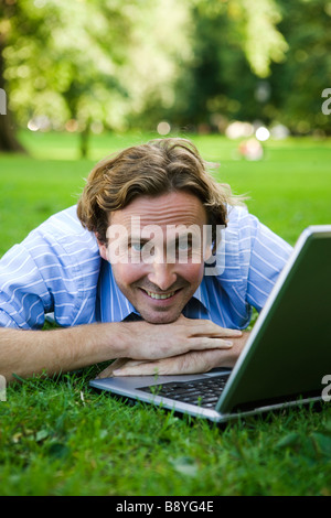 Ein Mann mit einem Laptop in einem Park Schweden. Stockfoto