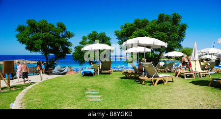 Der Rasen am Strand ist ein beliebter Treffpunkt für Touristen in Fig Tree Bay, Protaras, Zypern Stockfoto