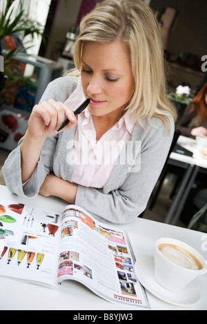 Porträt einer Frau mit einer Tasse Kaffee und liest eine Zeitschrift Schweden. Stockfoto