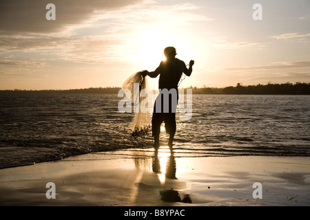 Fischer wirft sein Netz wie die Sonne über der Stadt La Barra, Nicaragua Stockfoto