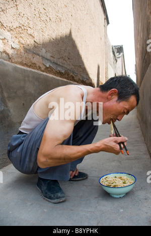 Mann isst eine Schüssel mit Nudeln in den Straßen von Pingyao, Provinz Shaanxi, China Stockfoto