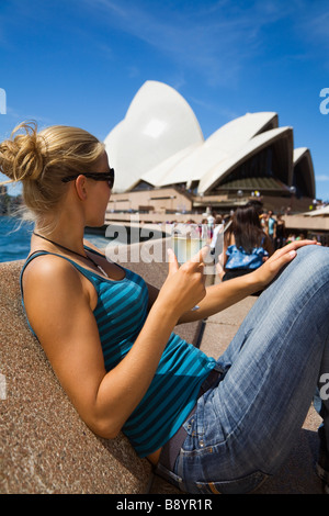 Eine Frau genießt einen Drink in der Opera Bar am Hafen von Sydney.  Sydney, New South Wales, Australien Stockfoto