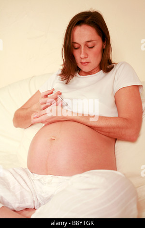 Junge hochschwangere Medikament missbrauchen oder diabetischen Frau injiziert sich mit einem Injektionsspritzen voller Heroin insulin Stockfoto