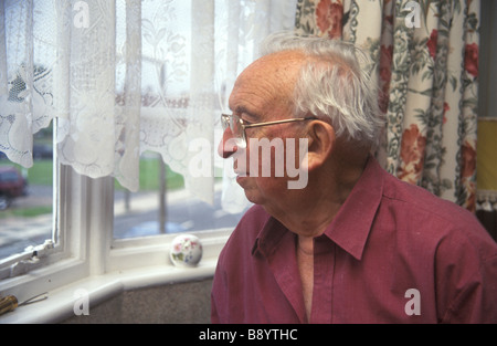 älterer Mann einsam und isoliert in der Heimat, starrte aus dem Fenster schauen Stockfoto