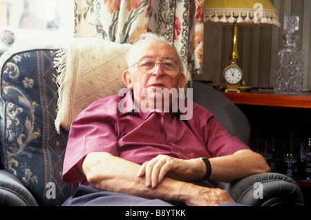 älterer Mann sucht einsam und isoliert in der Heimat mit Uhr im Hintergrund Stockfoto