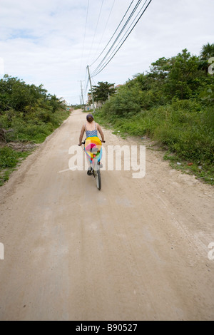 Junge Frau mit dem Fahrrad auf einem Sandweg auf Ambergris Caye, Belize. Stockfoto