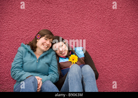 Zwei junge Frau Lachen und Spaß haben, als Freunde vor einem rosa Wand im Freien. Stockfoto