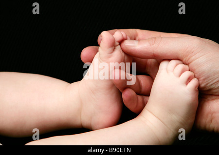 Eine Hand Erwachsenen und Baby Füße Nahaufnahme. Stockfoto