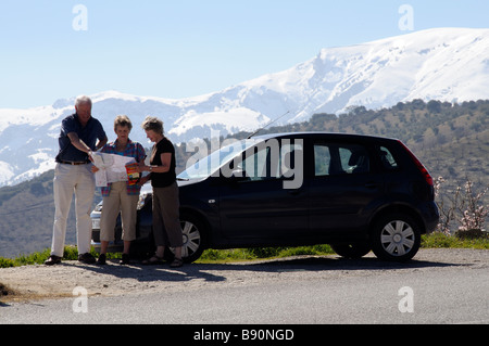 Touristen mit ihren Mietwagen Blick auf Karte mit Schnee bedeckt Gebirgshintergrund in der Sierra Tejeda Südspanien Stockfoto