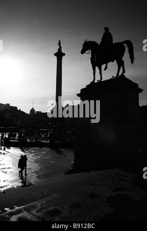 Statue von König George IV und Nelson Säule Silhouette durch die niedrige Wintersonne, Trafalgar Square, London Stockfoto