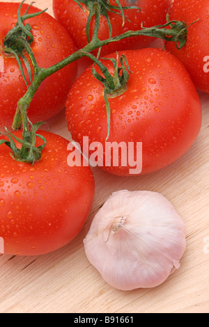 Taufrische rote Tomaten und Knoblauch auf ein Holz Schneidebrett Stockfoto