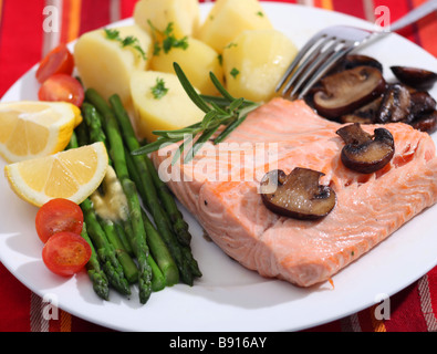 Gebratenes Lachssteak mit Champignons Spargel Kirschtomaten und abgerundet mit einem Zweig Rosmarin Kartoffeln serviert Stockfoto