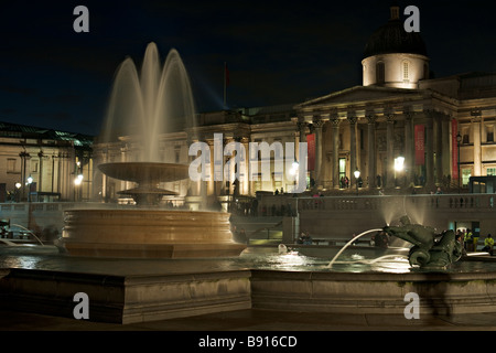 Trafalgar Square Brunnen London England UK beleuchtet in der Nacht der nationalen Küche ist im Hintergrund Stockfoto