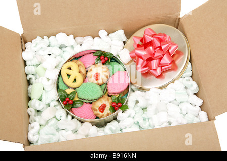 Eine Dose mit bunten Weihnachtsplätzchen verpackt in Erdnüssen und bereit für Mailing-weißer Hintergrund Stockfoto