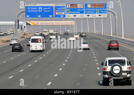 Dubai Autoverkehr auf modernen siebenspurigen Autobahn Autobahn zweisprachig Wegweiser für die Gantry-Ausfahrt zu den Flughafenterminals 1 und 4 United Arabische Emirate VAE Naher Osten Stockfoto