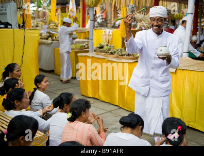 Priester, Weihwasser auf Teilnehmer in einer hinduistischen Zeremonie - Bali, Indoneisa Stockfoto