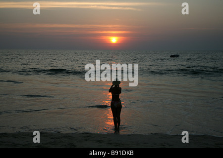 Ein Tourist nimmt ein Foto des Sonnenuntergangs auf Mobor Beach in Goa, Indien Stockfoto