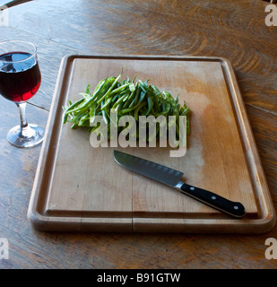 Ein Schneidebrett mit Jullienned grüne Bohnen, ein Santokumesser und ein Glas Wein für den chef Stockfoto