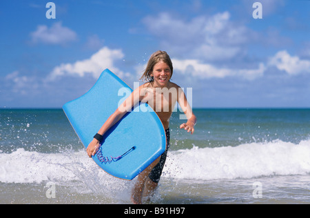 Junge running out of Surf mit Bodyboard Stockfoto