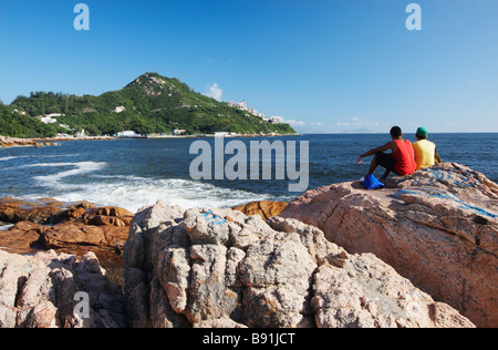 Jungen sitzen auf Felsen, Stanley, Hong Kong Stockfoto