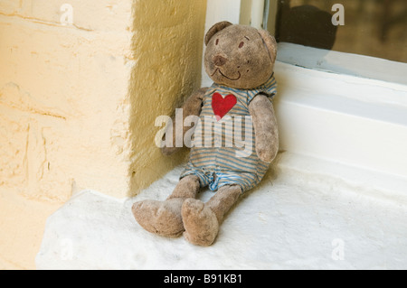 Grubby aufgegeben Teddybär auf einer Fensterbank Stockfoto