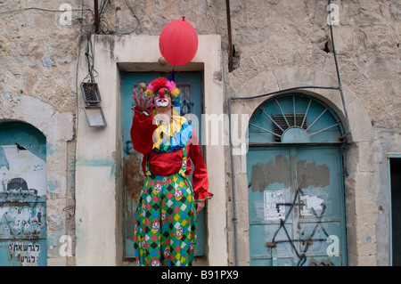 Ein jüdischer Siedler, der während der Purim-Zeit in der Al-Shuhada-Straße, die seit der zweiten Intifada in Hebron für palästinensische Händler gesperrt ist, als Clown gekleidet war Stockfoto