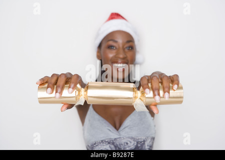 Frau lächelnd hält ein Christmas Cracker zu ziehen Stockfoto