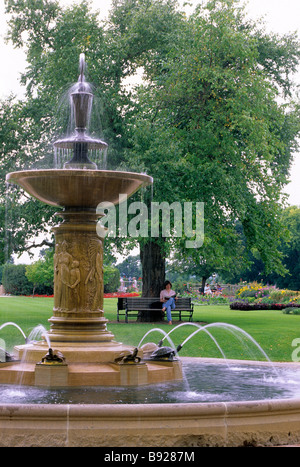 FRAU ENTSPANNT SICH IN DER NÄHE VON BRUNNEN IM SEE HARRIET ROSE GARTEN, LYNDALE PARK;  IM HERZEN VON MINNEAPOLIS, MINNESOTA.  SOMMER. Stockfoto