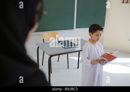 Kleiner Junge liest ein Schulbuch vor einer Klasse Dubai Vereinigte Arabische Emirate Stockfoto