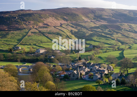 Hohe Aussicht auf schöne, sonnige Yorkshire Dales Dorf Burnsall im Tal von River Wharfe & mit steilen, Grün, Hügel jenseits - England, GB, UK. Stockfoto