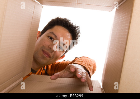 junge Männer, die etwas in einem Karton zu erreichen Stockfoto