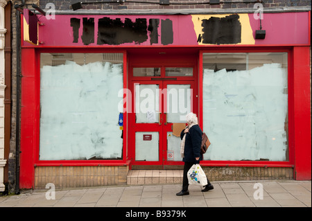 Eine Frau vorbeigehen ein Closed Shop (Dreschmaschinen Wein &amp; Schnaps) mit gemalten Fenster und Shop Name UK Stockfoto