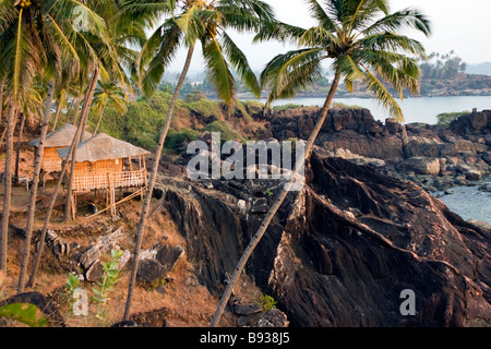 Felsigen tropischen Strand Aussicht mit Hütten auf Sonnenuntergang. Stockfoto