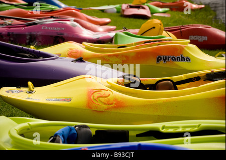 Farbenfrohe Kajaks Reihen sich am Ufer des Flusses am Tees Barrage International White Water Center mit der Tees Barrage Bridge, Großbritannien, an Stockfoto